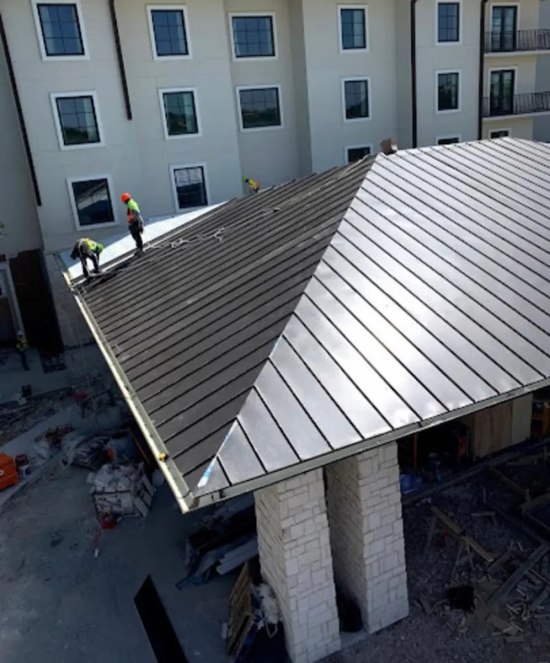 Crew installing standing seam metal roof panels on a commercial project in Boerne